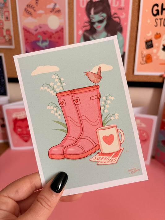 Hand holding a postcard with a red boot illustration against a pink background